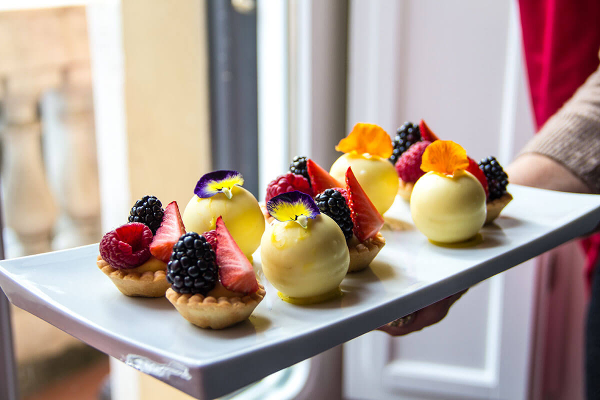 Mono-Portions of tartlet with red fruits and white chocolate sphere.